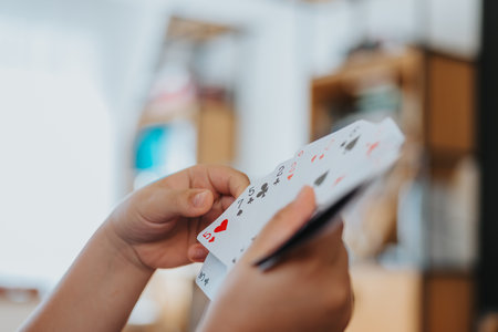 Child playing cards at home, having fun with a family game