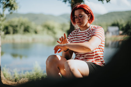 Young woman outdoors by a lake during summer on a sunny dayの写真素材