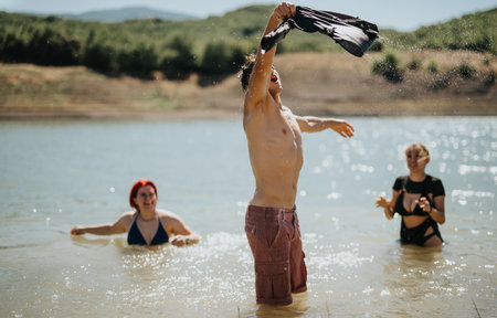 Friends enjoying a sunny day at the lake, engaging in fun and playful activitiesの写真素材