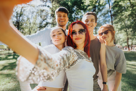 Joyful friends taking a selfie in a sunny park, smiling and enjoying a warm day togetherの写真素材
