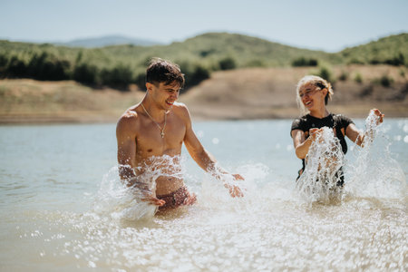 Happy friends splashing in the water and enjoying a sunny day at the lake, surrounded by natureの写真素材