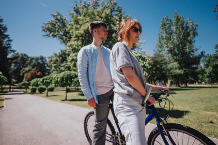 Couple enjoying a sunny day at the park with bicycles, leisure outdoor activitiesの写真素材