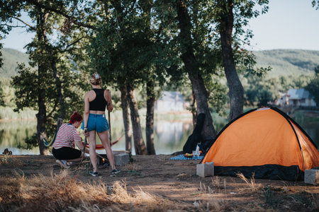 Friends enjoying a picnic by a tent in nature with mountains in the backgroundの写真素材