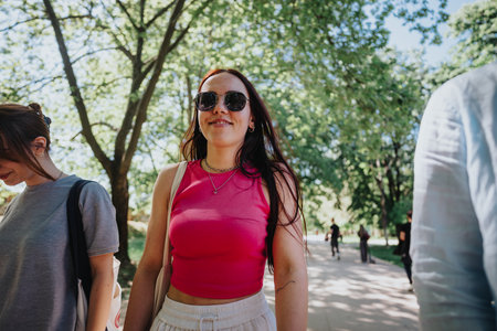 Friends enjoying a leisurely stroll and conversation in the park on a sunny day.