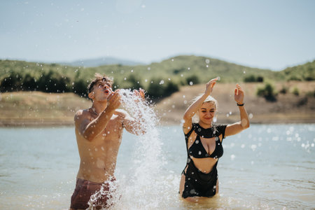 Happy couple playing in a lake on a sunny day, splashing water and having funの写真素材