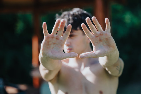 Young athletic man showing hands with calluses from intense sports training outdoorsの写真素材