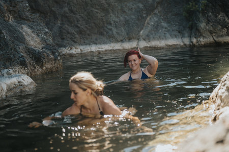 Two women cooling off in the river at the mountain on a sunny dayの写真素材