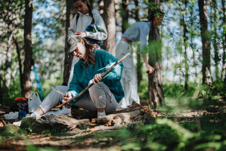 Young people enjoying a camping adventure in the forest carving wood and bondingの写真素材