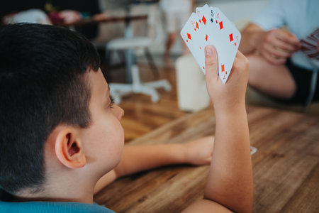 Child holding playing cards during a family card game at home