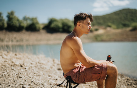 Young man enjoying a sunny day by the lake in summerの写真素材