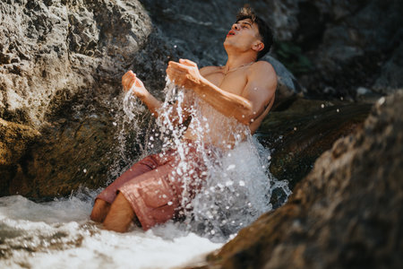 Man cooling off in a refreshing mountain river on a hot dayの写真素材