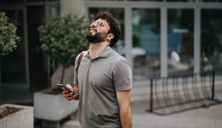 Disappointed businessman looking up while using smart phone outdoors.