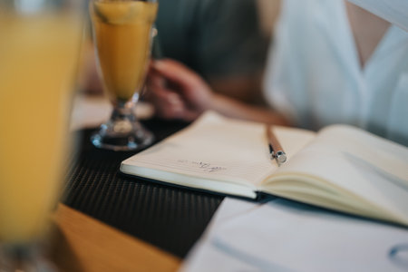 Business meeting in a coffee bar with open notebook and beverages on the tableの写真素材