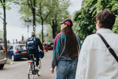 People walking in a city street surrounded by trees and carsの写真素材