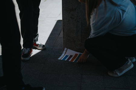 Young businesspeople outdoors in a meeting reviewing bar graph chartの写真素材