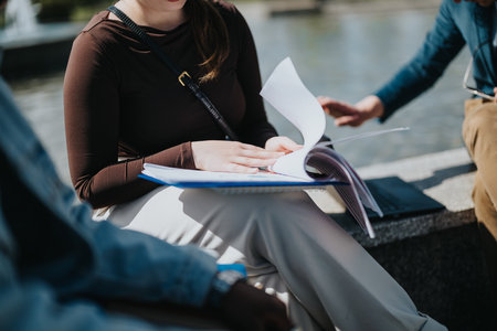 Young businesswoman reviews documents with colleague outdoors