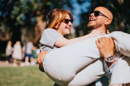 Joyful couple enjoying a sunny day in the park while laughing and embracingの写真素材