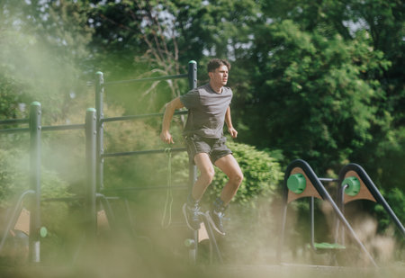 Man performing calisthenics workout in park, exercising on outdoor gym equipment for fitness
