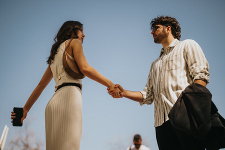 Business executives meeting outdoors with a handshake under a clear skyの写真素材
