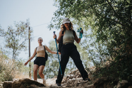 Two young women enjoying a sunny summer hike together in a forestの写真素材