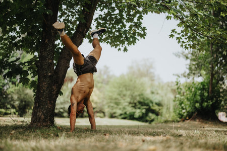 Man performing handstand exercise in park showcasing strength and balanceの写真素材
