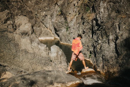 Man cooling off by the river in a mountain landscape with rocky cliffs and natural waterの写真素材