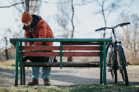 Man taking a break on a park bench with his bicycle on a sunny dayの写真素材