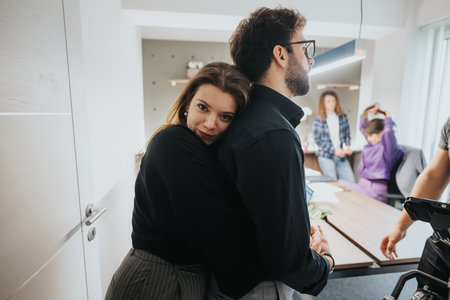Colleagues flirting at work and sharing a warm hug in a lively office environment, capturing a...
