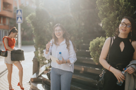 Businesswomen engaging in casual outdoor meeting, discussing work and enjoying a sunny day in the cityの写真素材