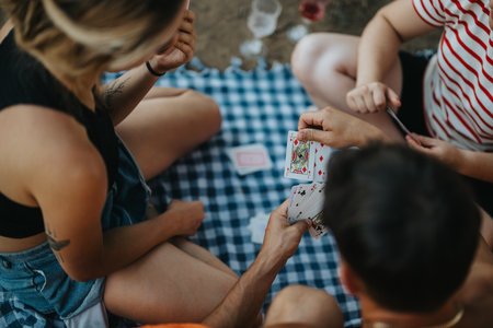 Friends enjoying a relaxed picnic while playing cards in natureの写真素材