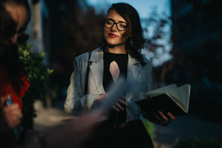 Confident young businesswoman holding notebook in urban setting, planning and discussing