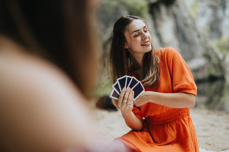 Young woman enjoying a card game during picnic in nature, smiling and having fun