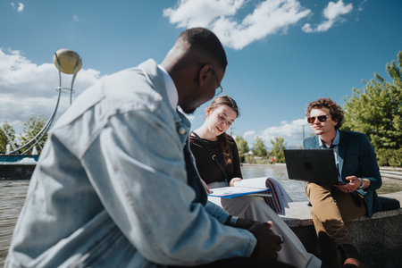 Diverse group of business professionals engaged in an outdoor meeting in a city parkの写真素材