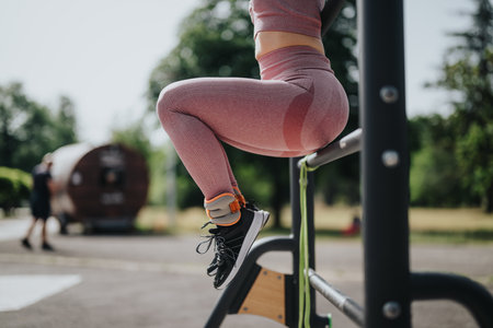 Woman doing calisthenics workout in park on a sunny day, focusing on leg raisesの写真素材