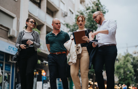 Group of business professionals walking and discussing work outdoors