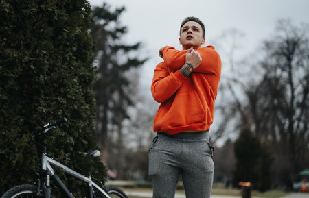 Young man taking a break from cycling in the park on a cloudy dayの写真素材