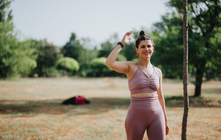 Woman exercising in park performing calisthenics workout on a sunny day.