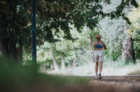 Woman jogging in park on sunny day, staying fit and healthy in outdoor environment