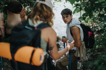 Group of friends hiking through forest trail with backpacks and trekking poles
