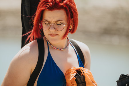 Young woman with red hair enjoying a sunny day by the lake wearing a blue swimsuit
