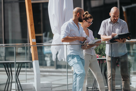Business team discussing project details outdoors on a sunny day