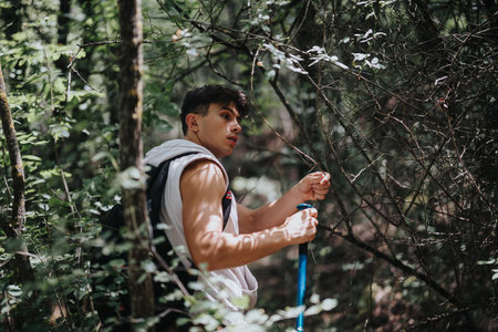 Young man hiking in a forest, enjoying nature and adventure on a sunny dayの写真素材