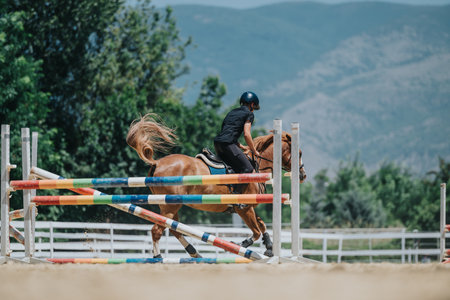 Horse rider jumping over colorful hurdles during an equestrian competition in an outdoor arena...