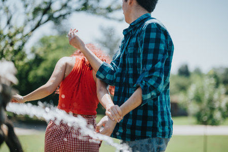 Group of friends having fun at a sunny park fountain on a warm dayの写真素材