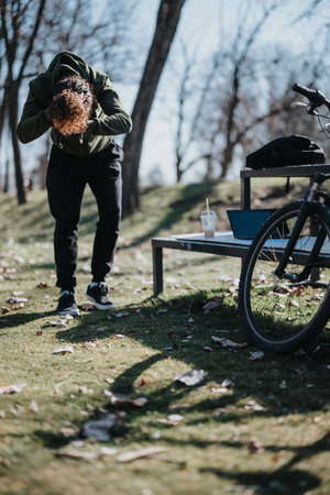 Young man enjoying a sunny weekend away, stretching near his bicycle in a peaceful park settingの写真素材