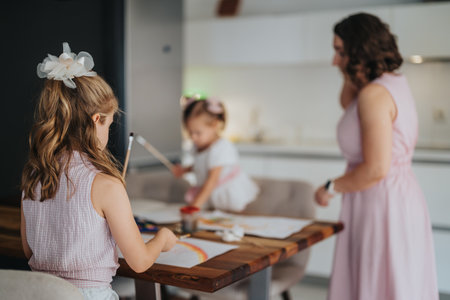 Young mother painting and drawing with her little daughters at homeの写真素材