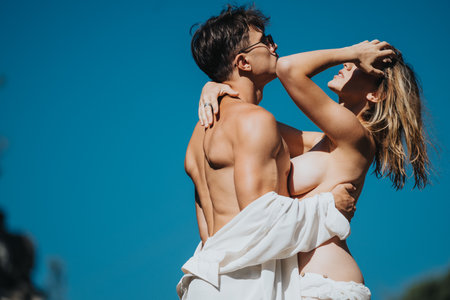 Romantic couple embracing under a clear blue sky in a passionate moment