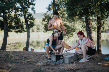 Friends having a picnic in nature, enjoying a barbecue by the lakeの写真素材