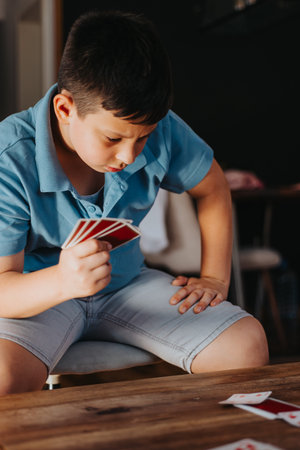 Young boy playing cards intently in a home settingの写真素材