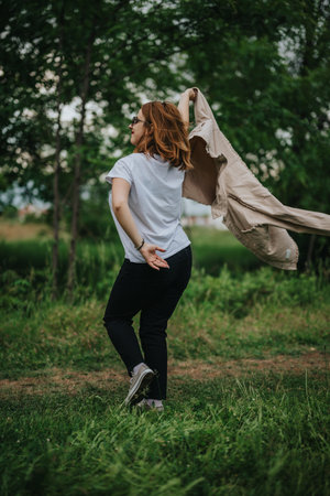 Woman joyfully walking in nature with jacket over her shoulder